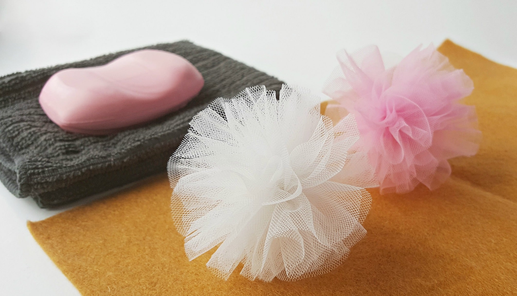 A pink and white soap and tulle flower on a piece of cloth.