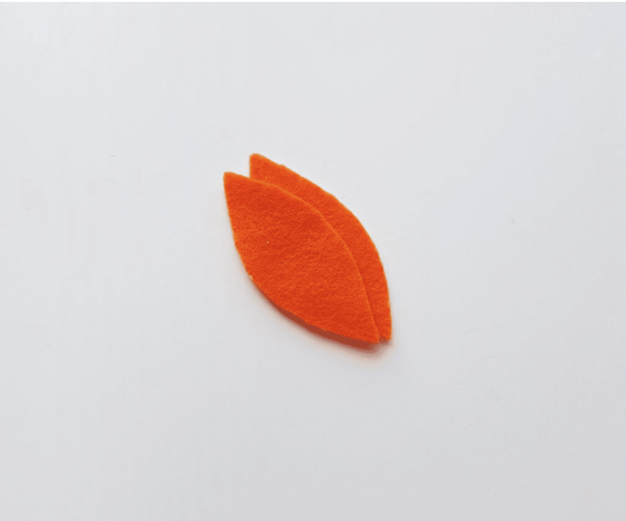 Two small orange felt cutouts shaped like leaves are placed on a plain white surface, perfect for adding a festive touch to your turkey craft project.