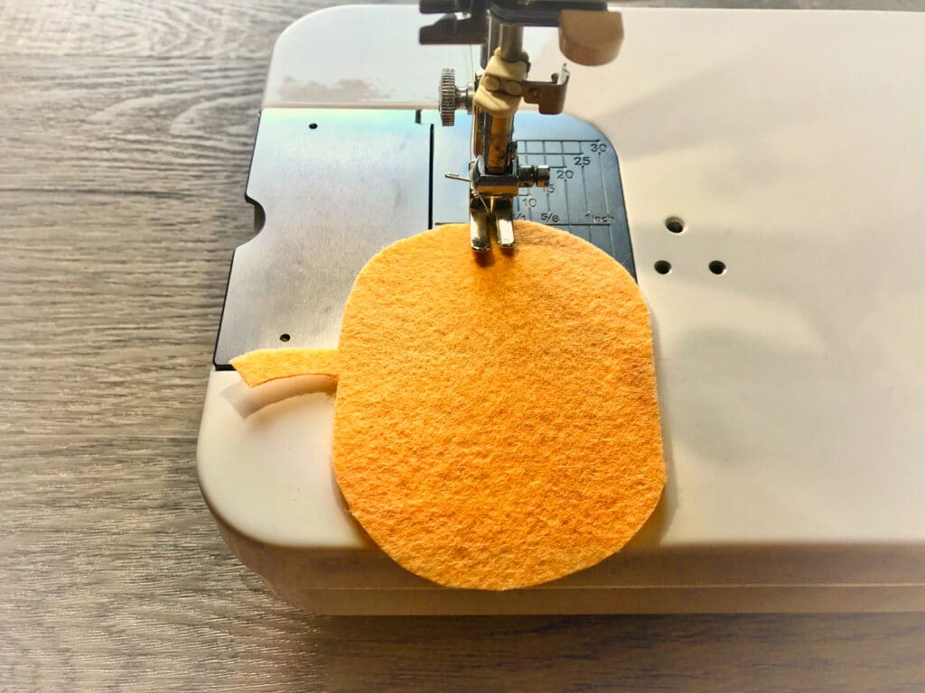 orange felt pumpkin under sewing machine foot and needle