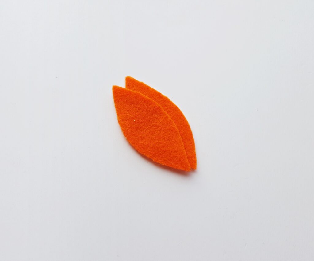 two orange felt feathers against white background