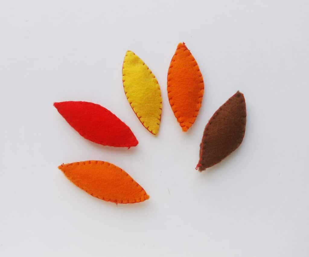 stuffed felt feathers in different colors against white background