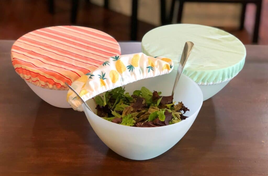Three bowls with salad in them on a table.