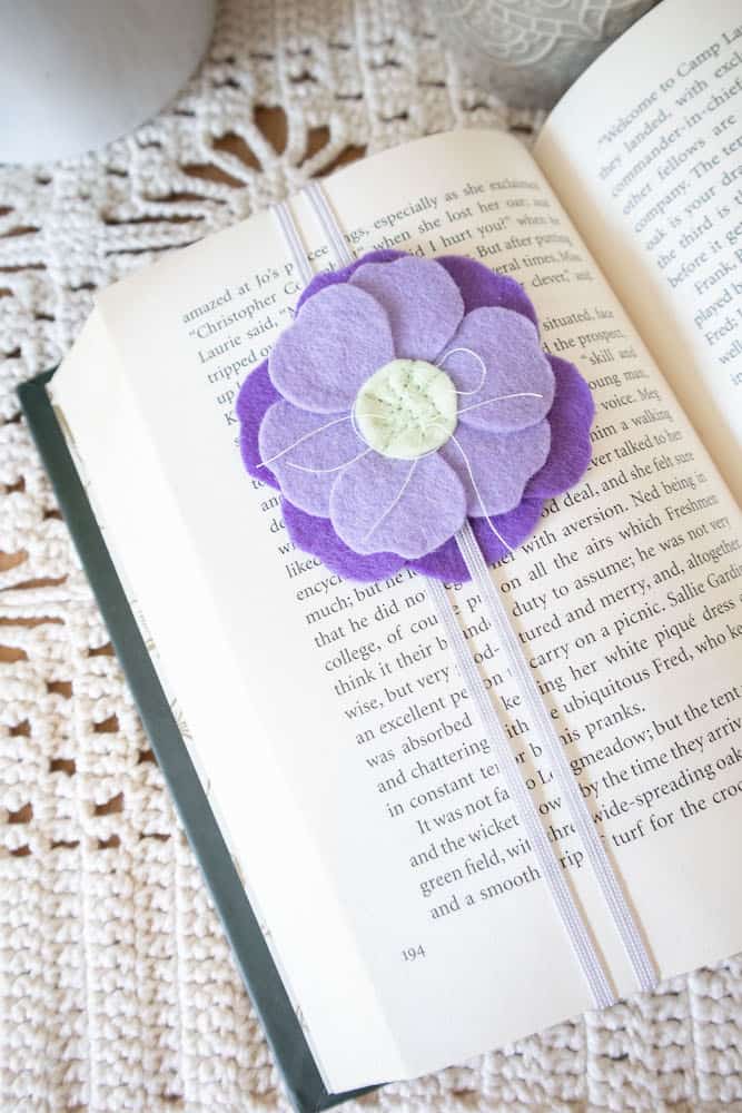 A purple felt flower bookmark on an open book.