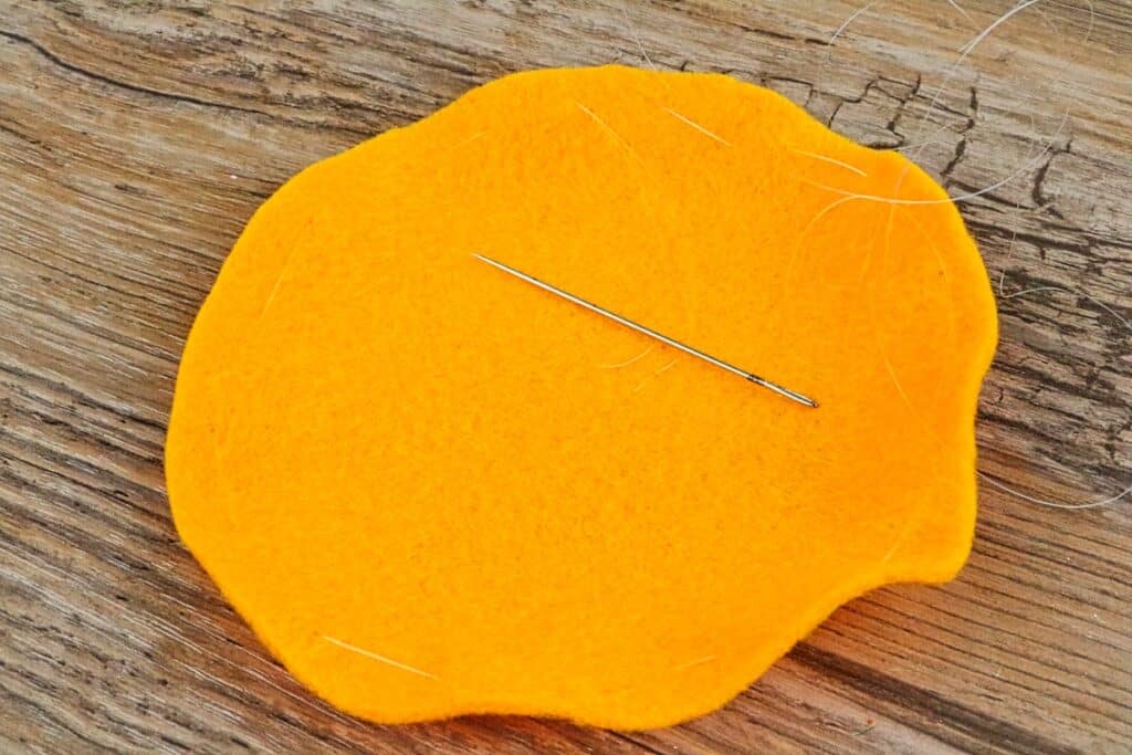 mini felt pumpkin on table with thread and needle