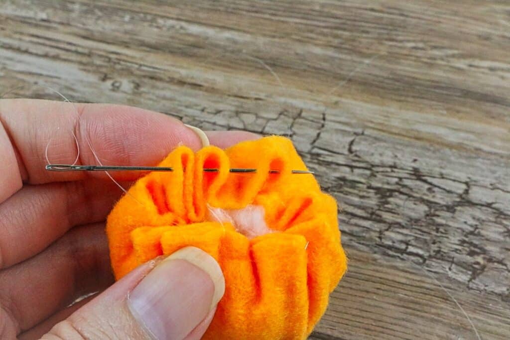 mini felt pumpkin rolled around cotton ball with needle and thread