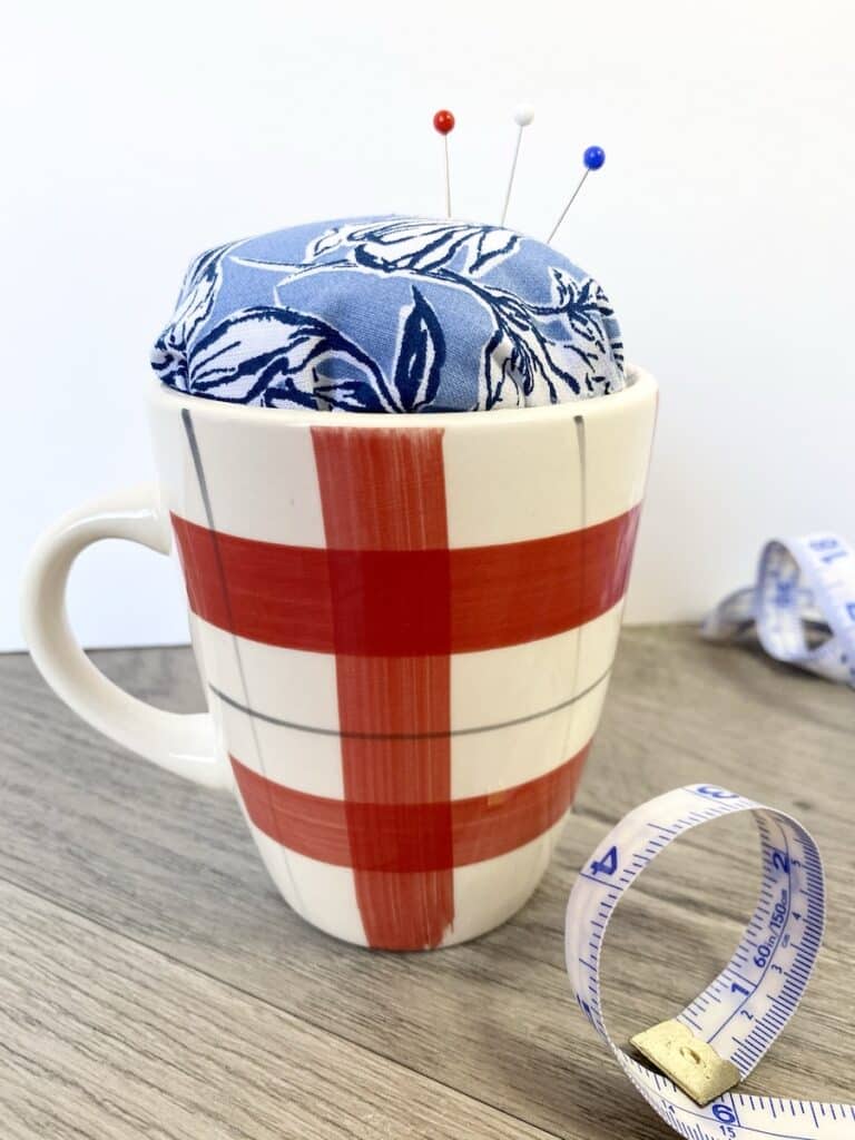 teacup pin cushion with ribbon on table