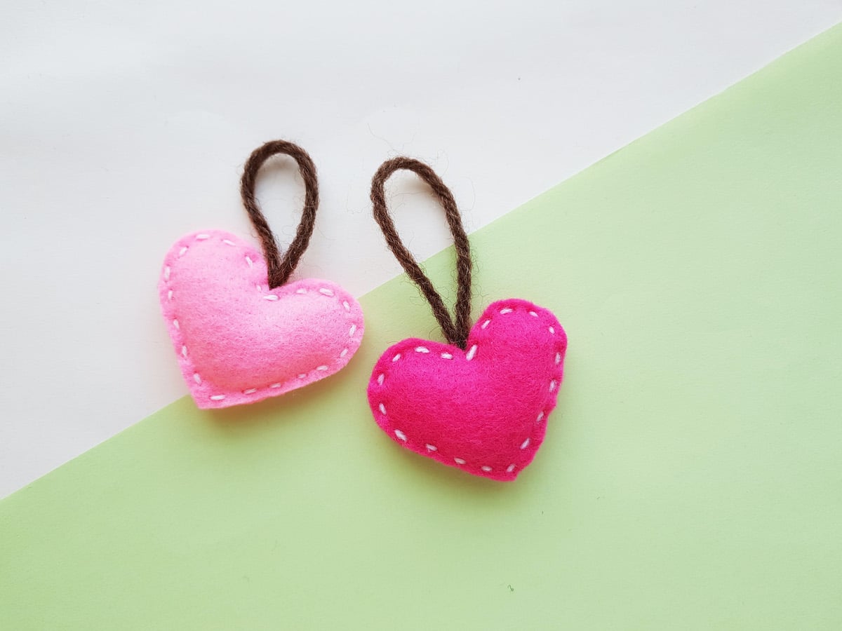 pink felt heart plushies on green background
