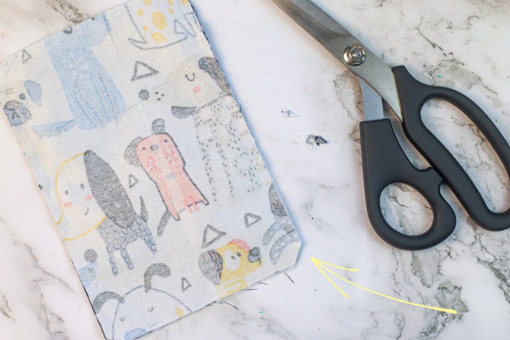 A pair of scissors next to a piece of fabric with dogs on it.