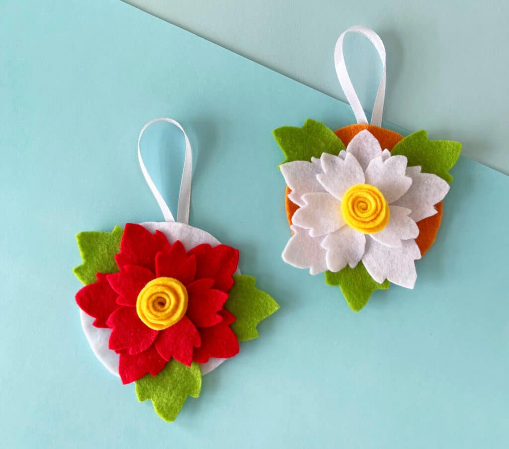 Two felt flower ornaments on a blue background.