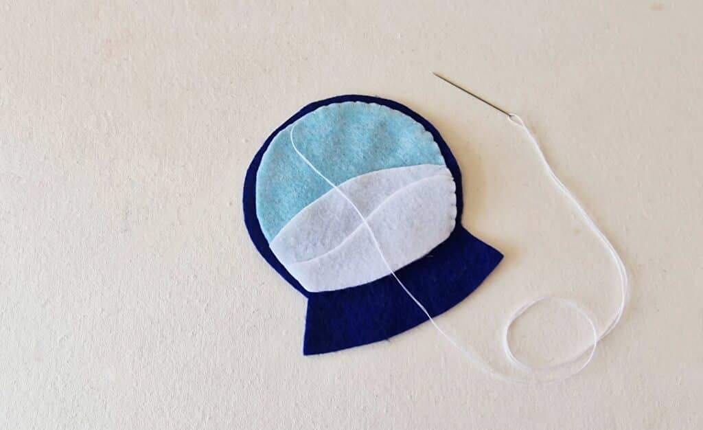 A blue and white felt hat with a needle and thread.