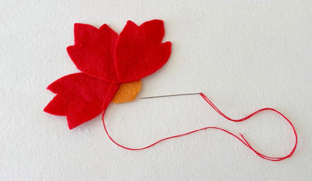 A red felt flower with a thread attached to it.