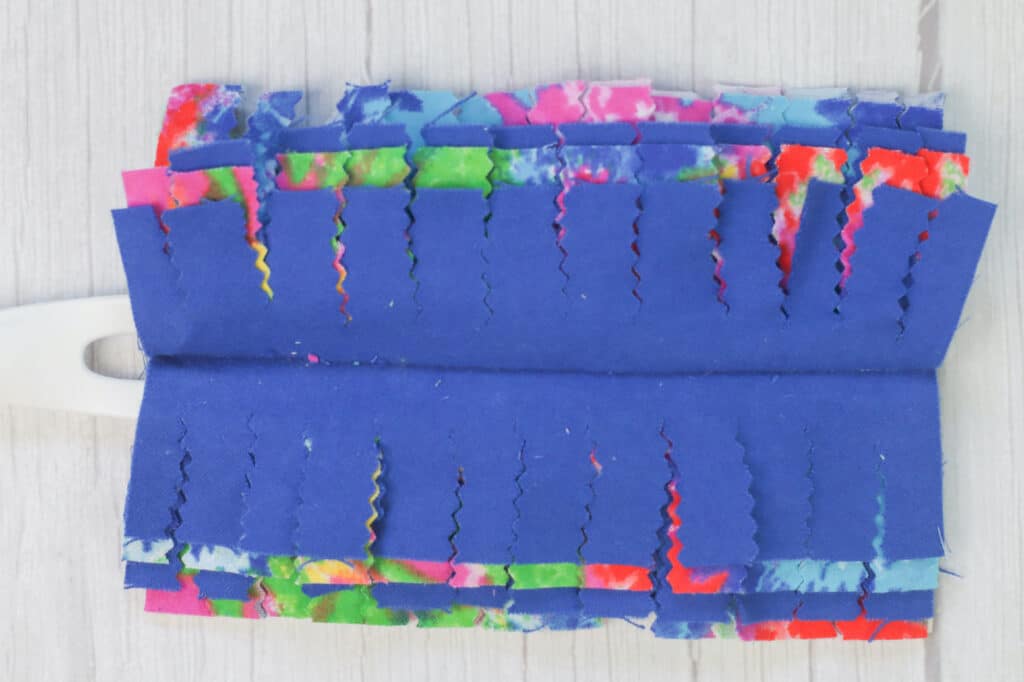 A blue cloth with colorful strips of fabric on it.