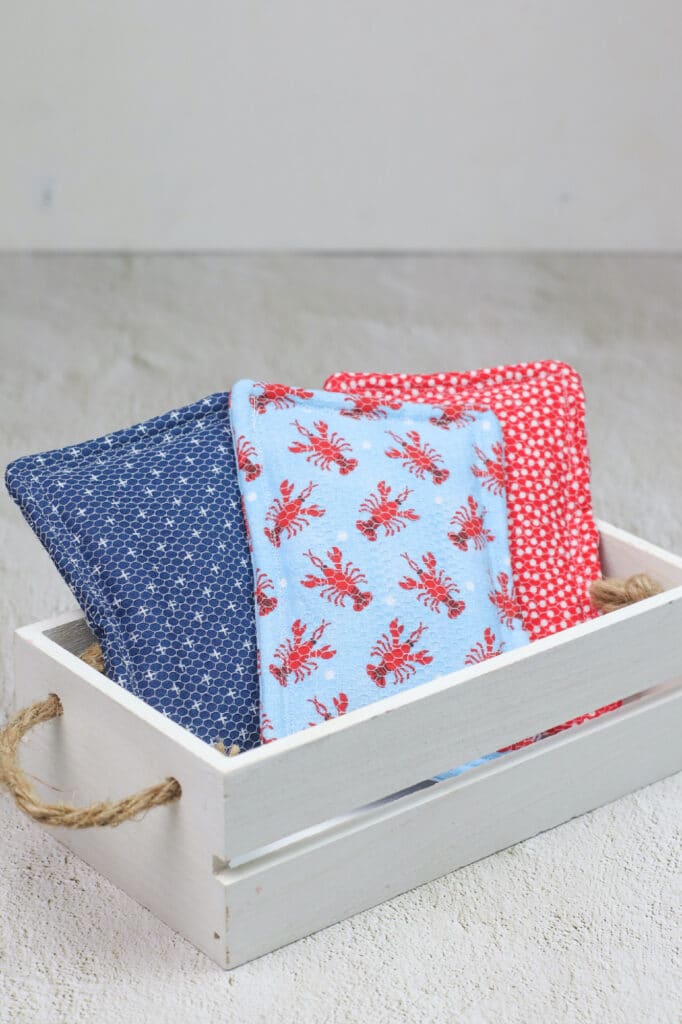 A wooden crate with three blue and red blankets in it.