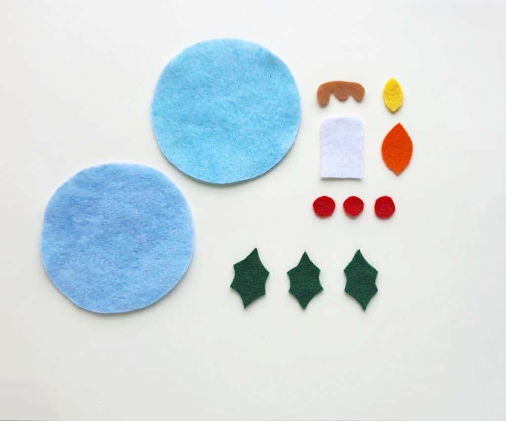 A set of blue felt candle ornaments with holly leaves and berries.