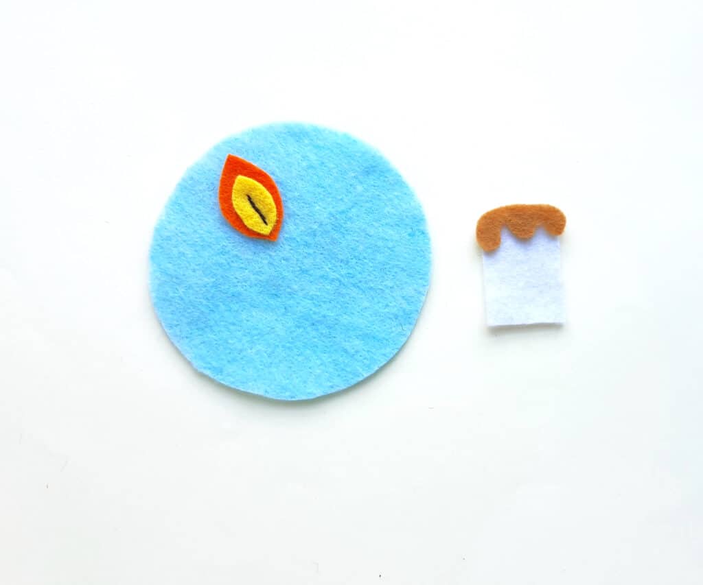 A blue felt circle with a candle ornament on it.
