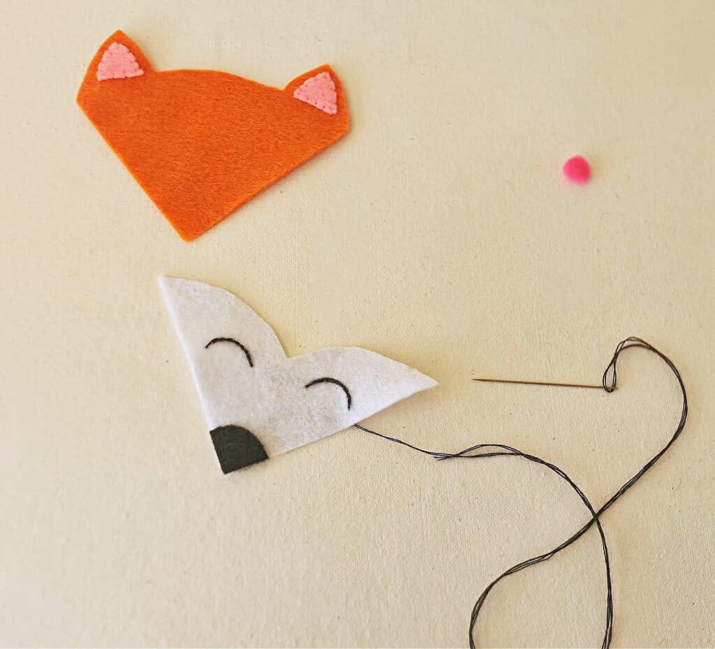 A felt fox is hanging on a wall.