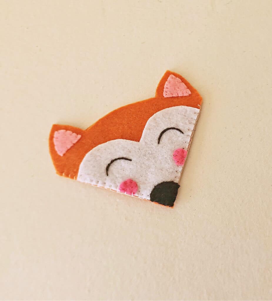 A felt fox with pink eyes on a white wall.