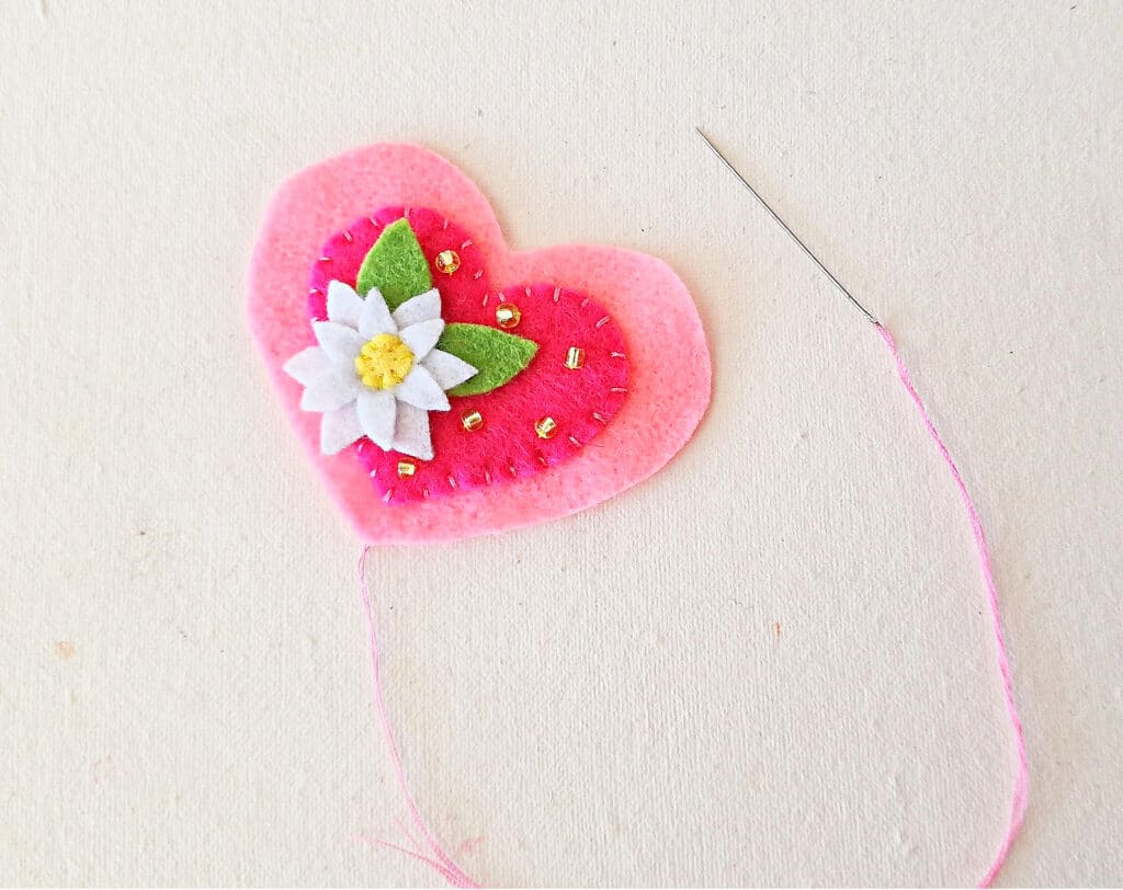 A pink felt heart with a flower on it.