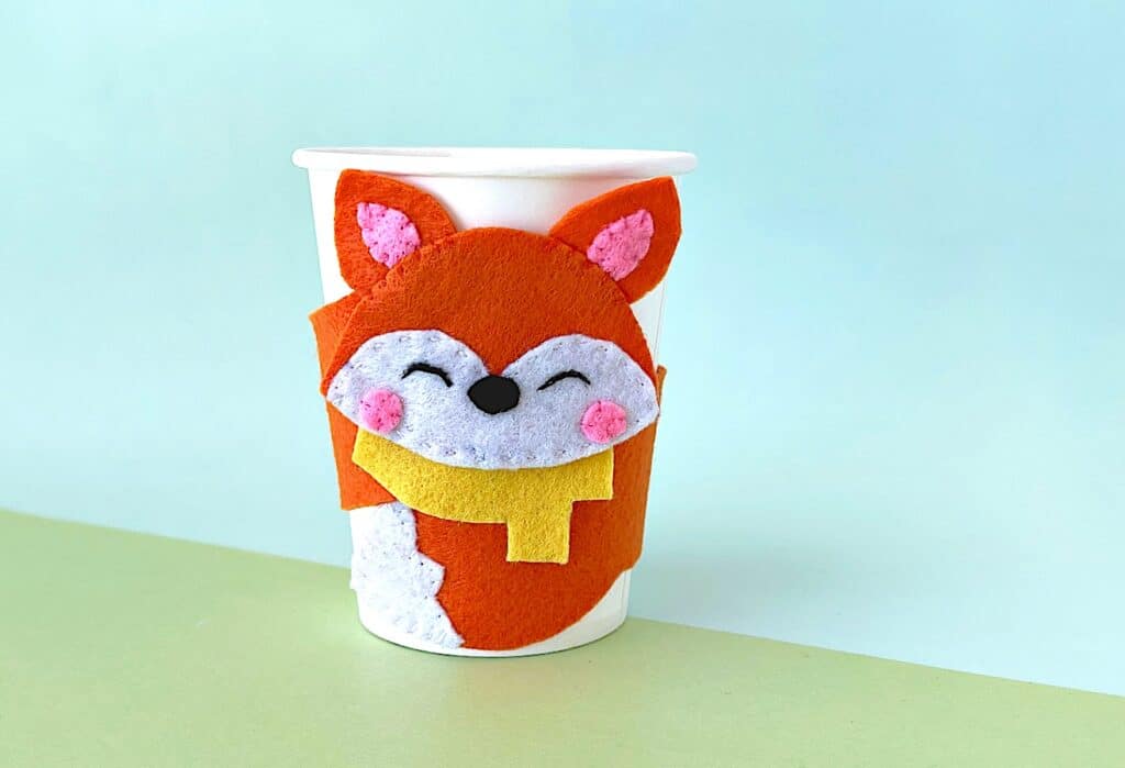 A felt fox cup cozy wrapped around a coffee cup