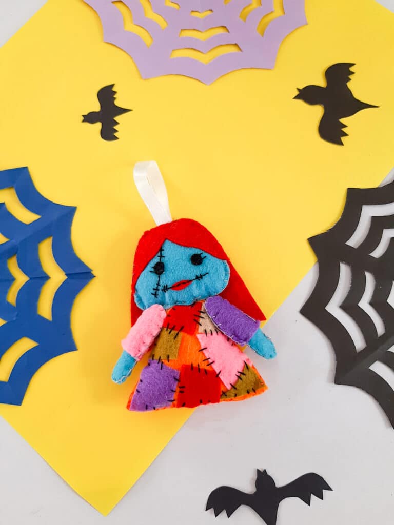 A halloween doll with bats and spiders on a yellow background.