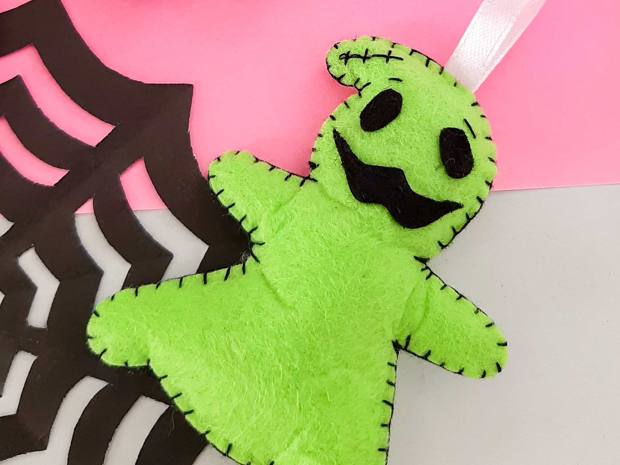 A green ghost stuffed animal on a pink background.