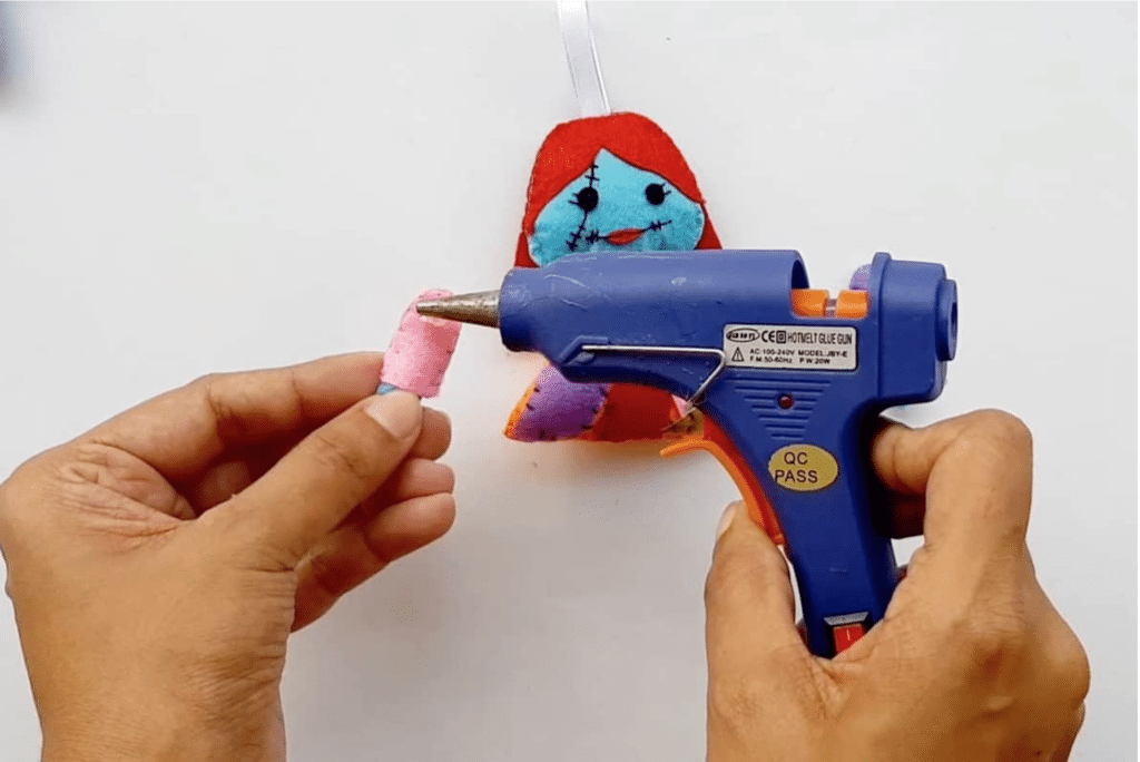 A person is using a glue gun to make a stuffed animal.