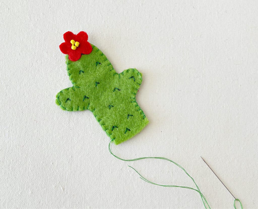 A felt cactus with a red flower on it.