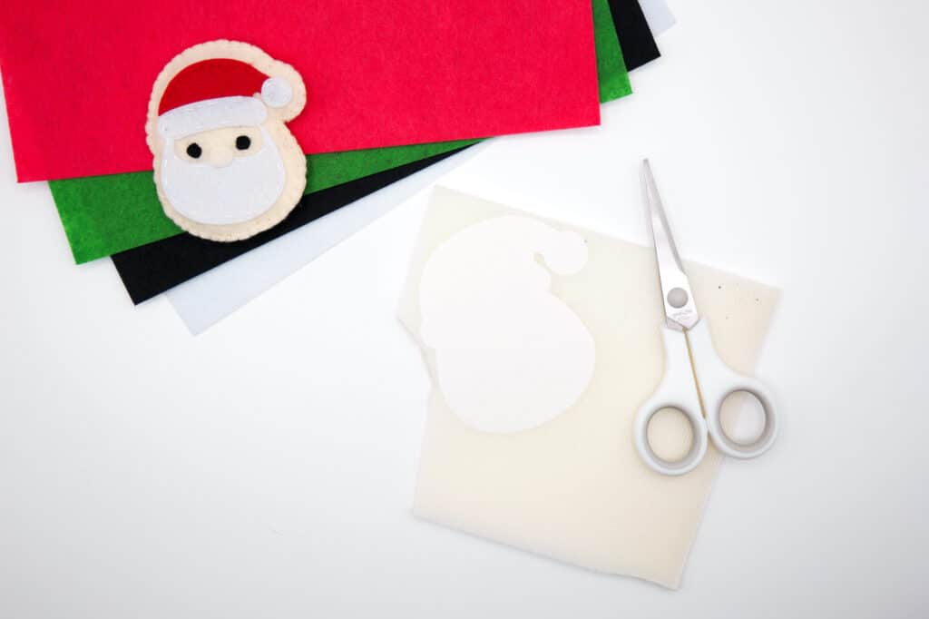 A santa claus craft with scissors and felt.
