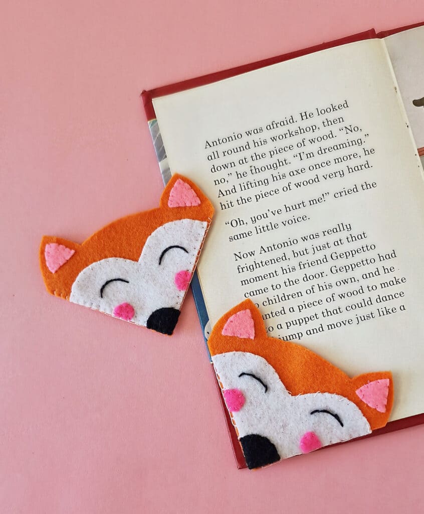 Two felt fox bookmarks on a pink background.