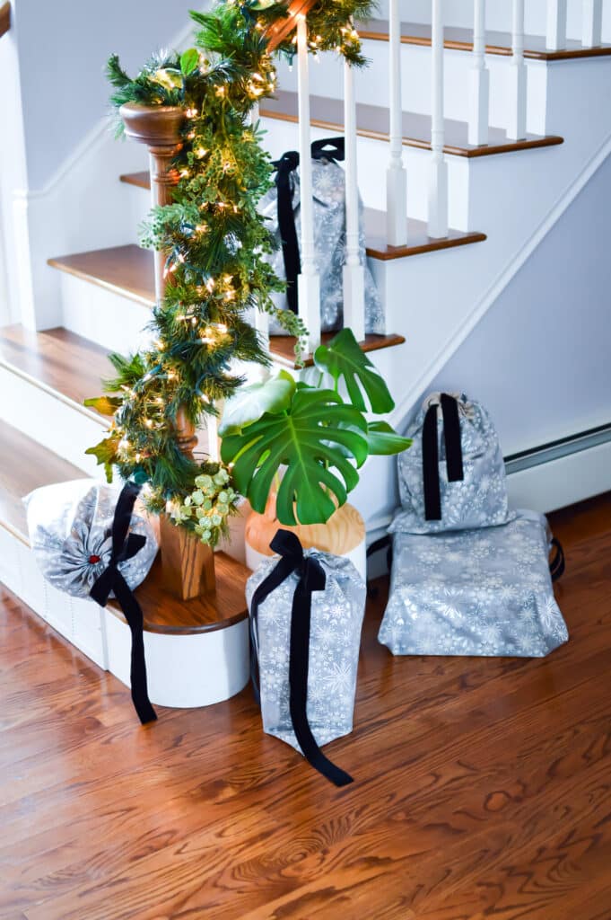 A christmas tree and gifts on the stairs.
