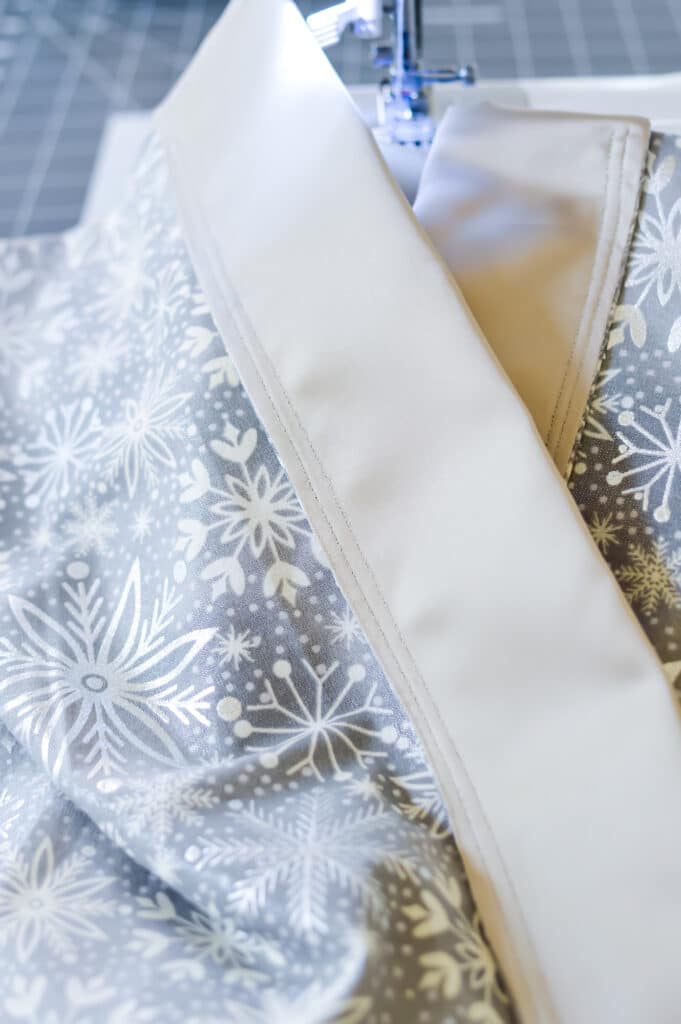 A fabric with snowflakes on it is being sewn.