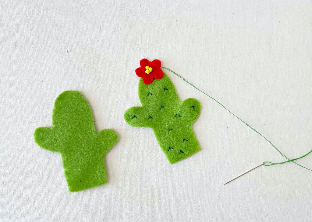 Two felt cactus ornaments with a red flower.