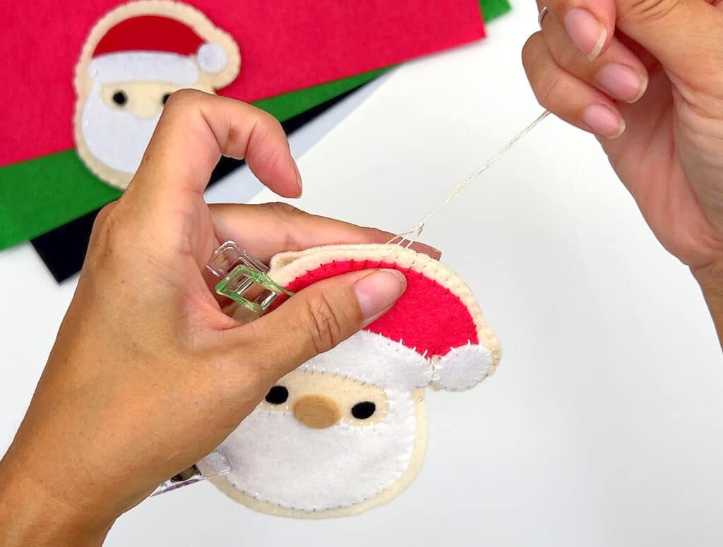 A person is making a felt santa claus ornament.