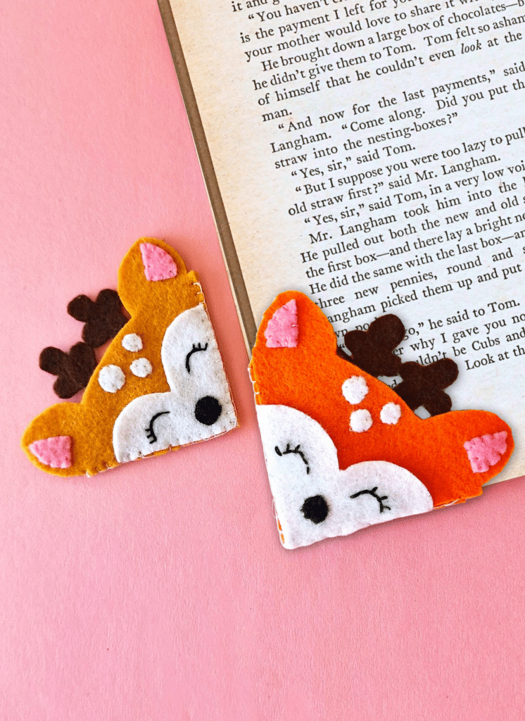 Two felt deer bookmarks on a pink background.