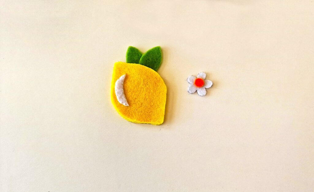 Felt Lemon Step 4 -A lemon and a flower on a white surface.
