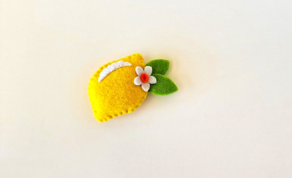 Felt Lemon Step 9 - A lemon brooch with a flower on it.
