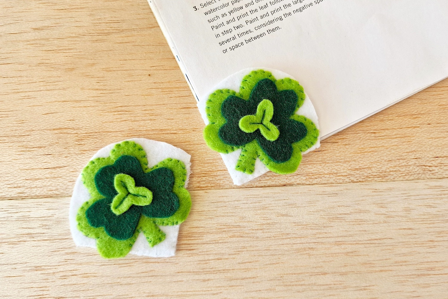 Two felt shamrock bookmarks on top of a book.