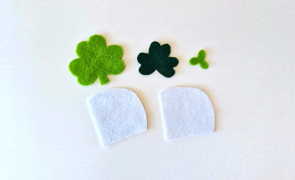 Felt Shamrock Bookmark Step 1 - A group of felt clovers and a small white object.