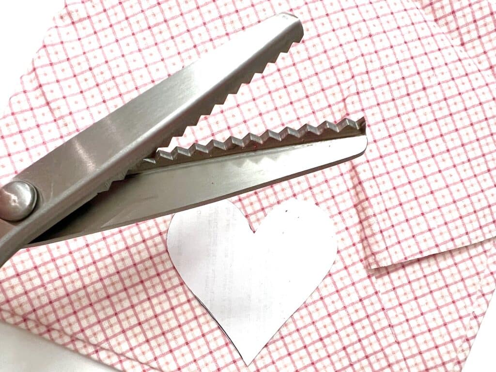 A pair of scissors on a cloth with stacked hearts.