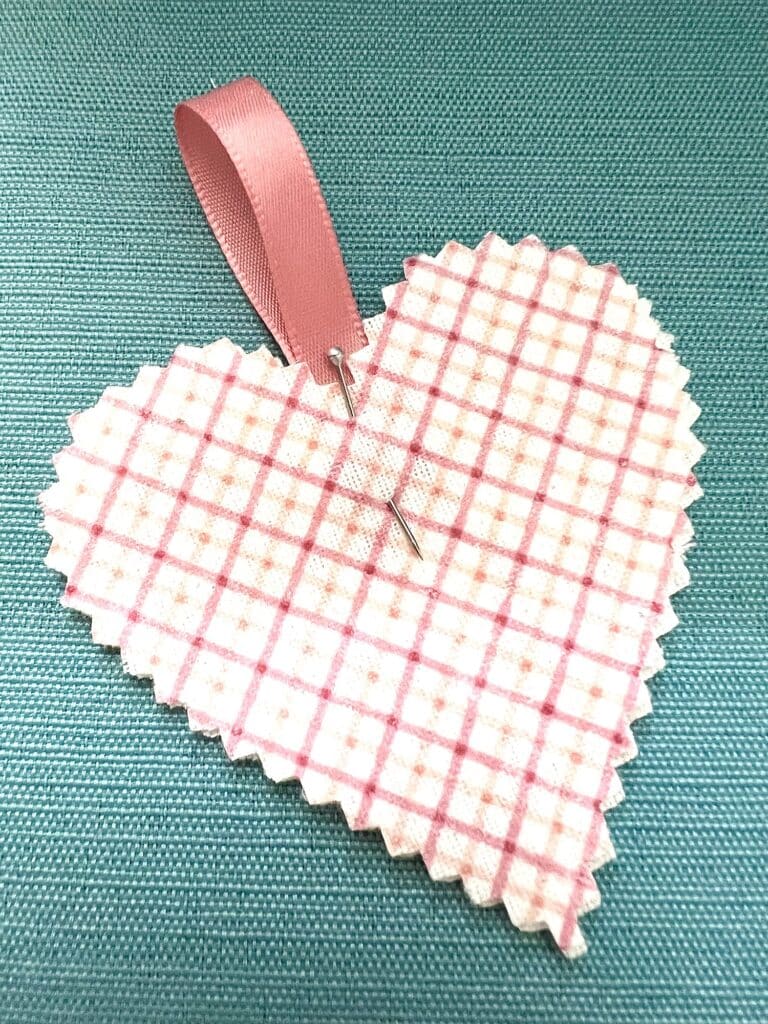 A pink and white stacked hearts bookmark on a blue background.