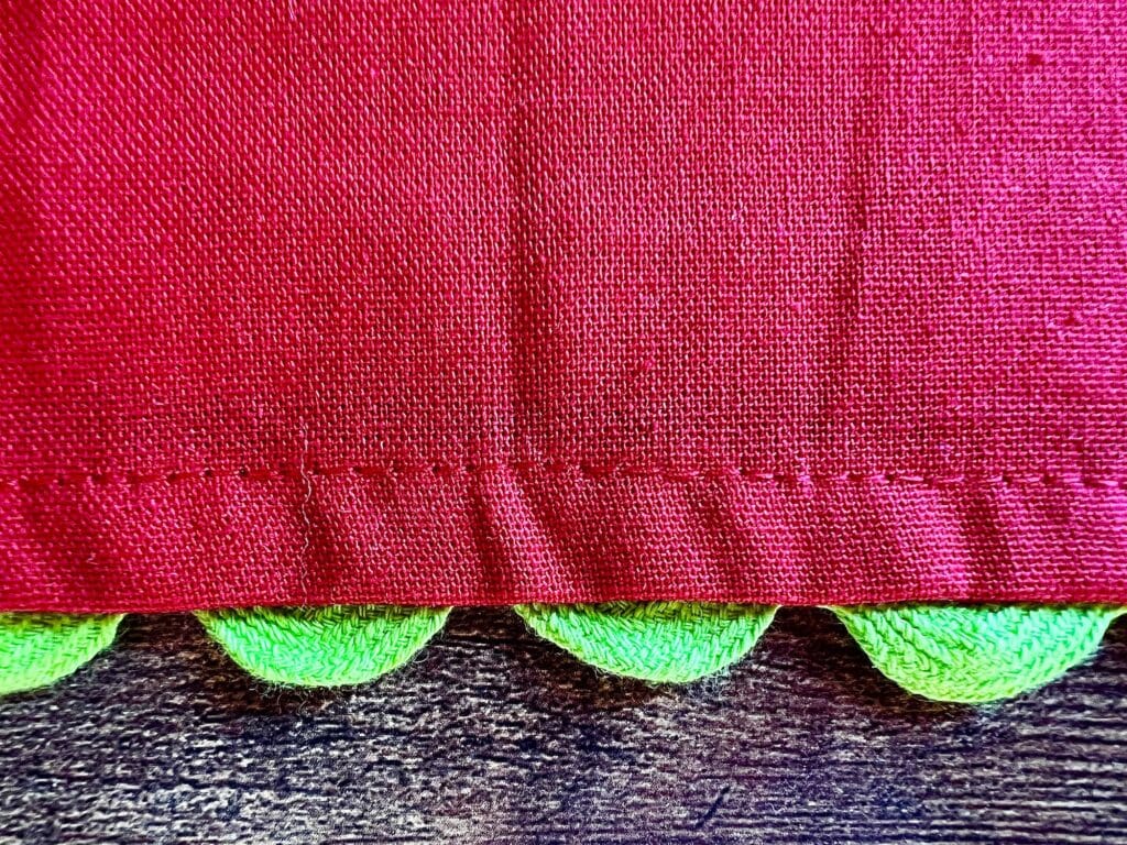 A close up of a red and green fabric with a rick rack trim.