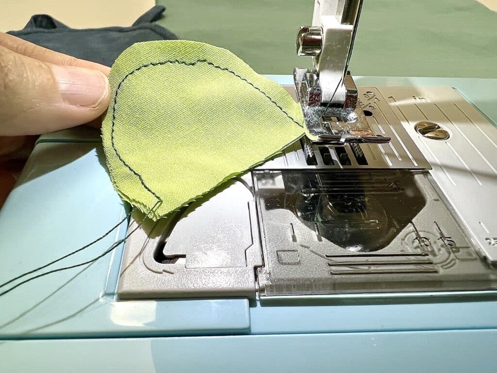 A person using a sewing machine to sew a piece of fabric with a turtle.