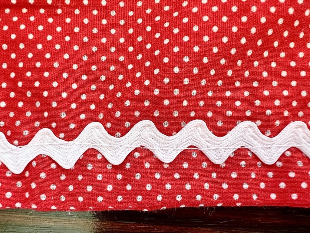 A red and white polka dot apron with white trim and rick rack embellishments.