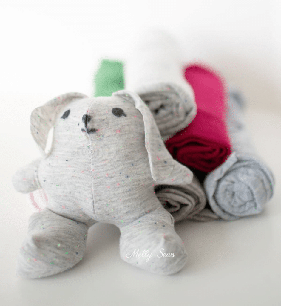 A adorable stuffed bunny is peacefully nestled on a stack of fluffy towels.