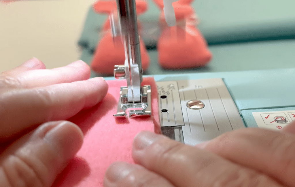 A person using a sewing machine to sew a piece of fabric.