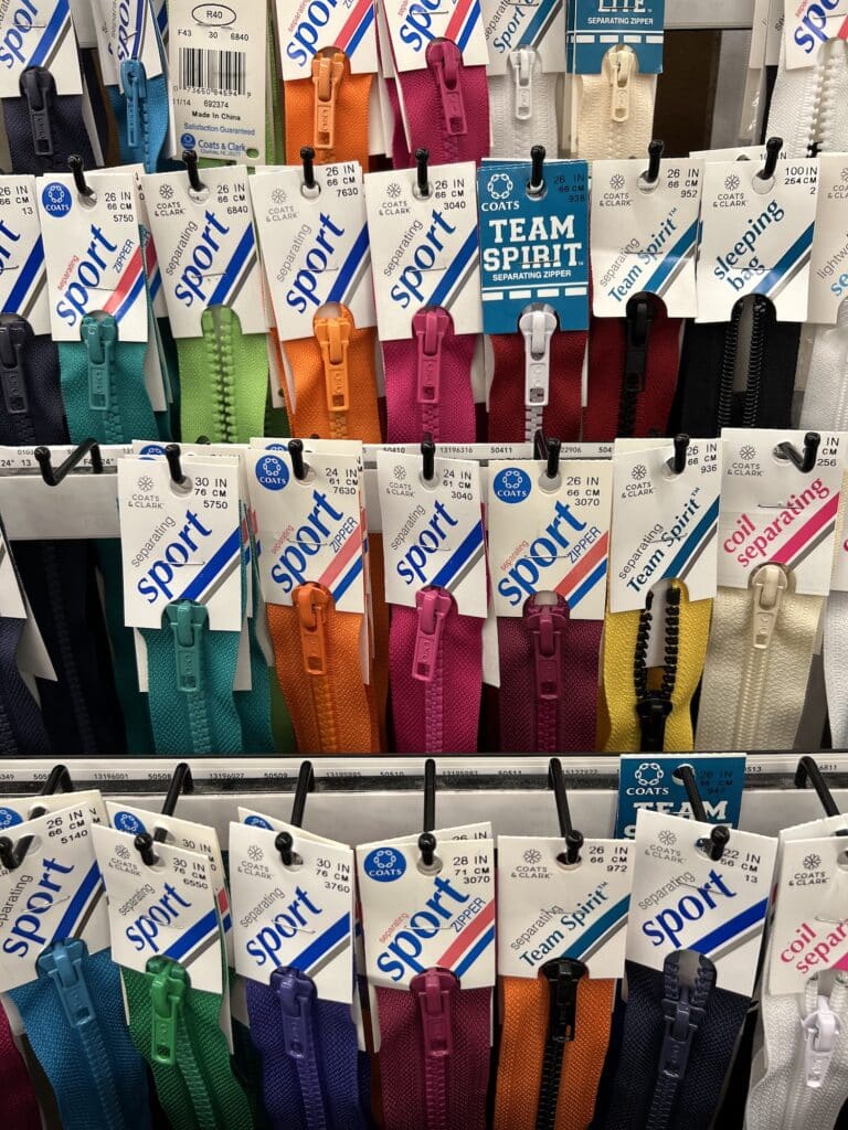 A variety of colored zippers, along with other sewing notions, are on display in a store.