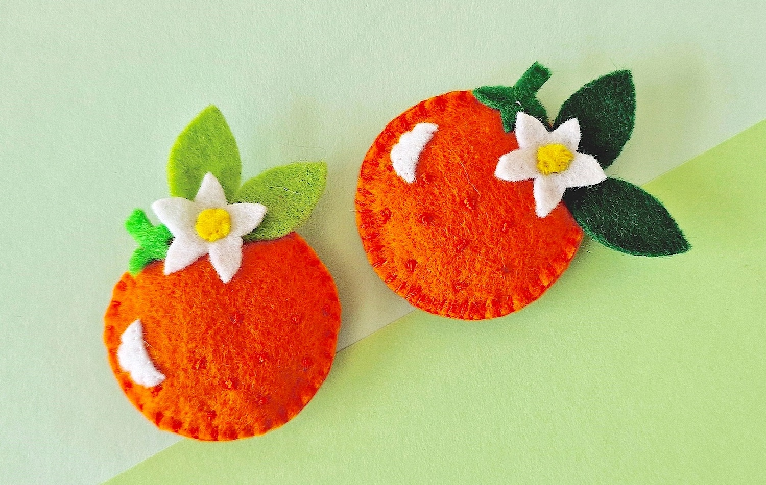 Handcrafted felt oranges with white flowers on a dual-toned background.