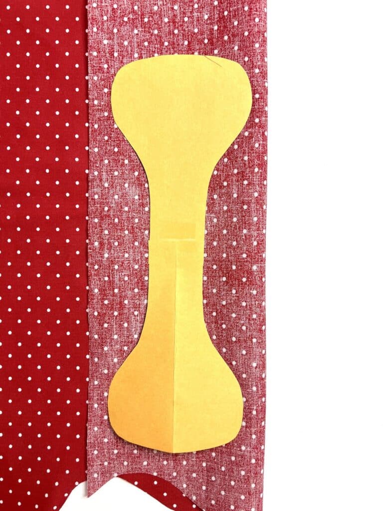 A yellow pattern piece on a red and white polka dot fabric background.