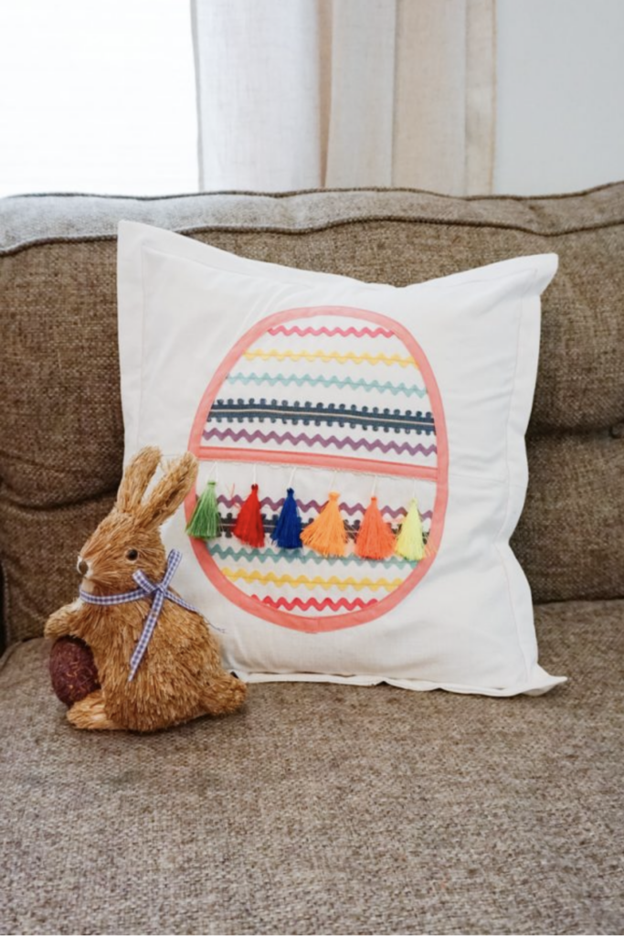 A cushion featuring a colorful, patterned egg design sits next to a decorative rabbit figurine on the sofa, echoing bunny sewing patterns for a charming touch.