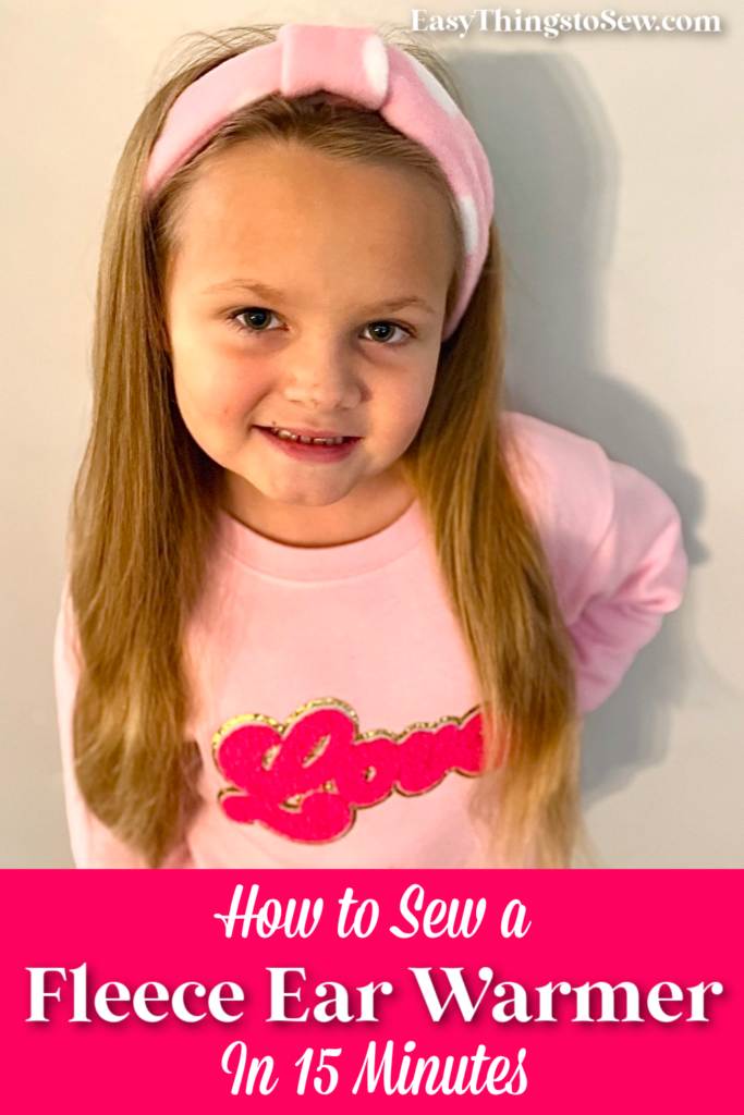 Young girl with long hair wearing a pink fleece headband and sweater, standing against a plain background. Text on the image reads: "How to Sew a Fleece Ear Warmer in 15 Minutes.